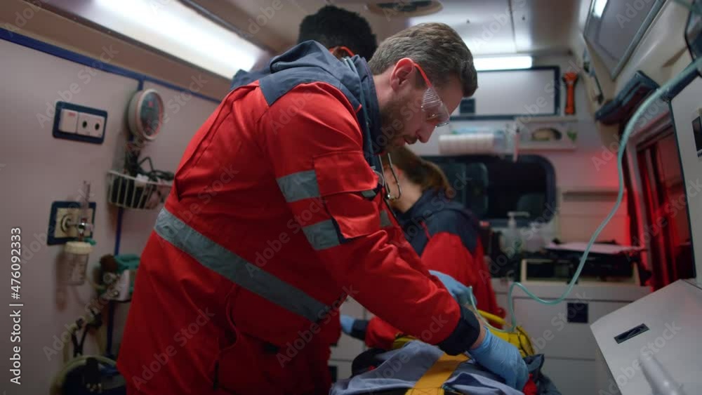 Emergency doctors performing first aid help to man in emergency car Emergency doctors performing first aid help to man in emergency car
