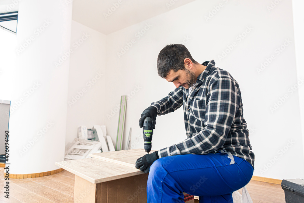 The carpenter finalizing the assembly of the kitchen shelf The carpenter finalizing the assembly of the kitchen shelf