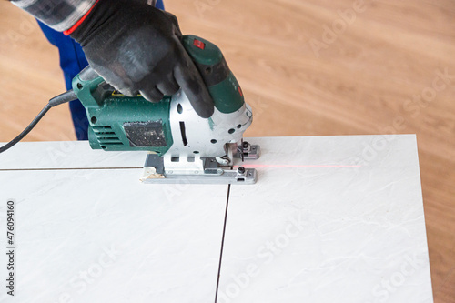 Close-up of corded jigsaw cutting a part of the wooden surface (board)