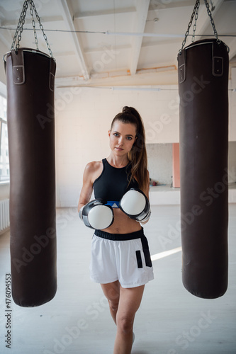 Beautiful kickboxing woman training with bag in fitness studio.