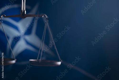 Fotografia Conceptual image of scales of justice on flag of NATO background as symbol of justice, collective defence