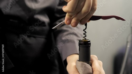 A close-up of a corkscrew twisting into a bottle of red wine. A waiter opens a bottle of red wine with a real cork in an elite restaurant. A man is opening a bottle of vine.