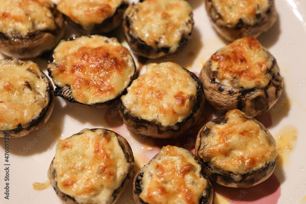 Baked fresh royal champignons filled with sour cream with onions and sprinkled with melted parmesan cheese