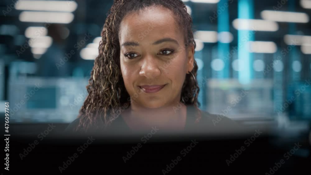 Portrait of African American Female IT Specialist Working on Desktop in Data Center. System Administrator Works on Web Services, Cloud Computing, Server Analytics, Cyber Security Maintenance, SAAS