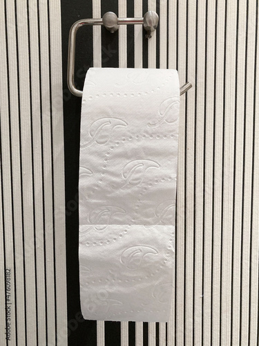 Pełna rolka papieru toaletowego wiszacego na uchwycie w toalecie.