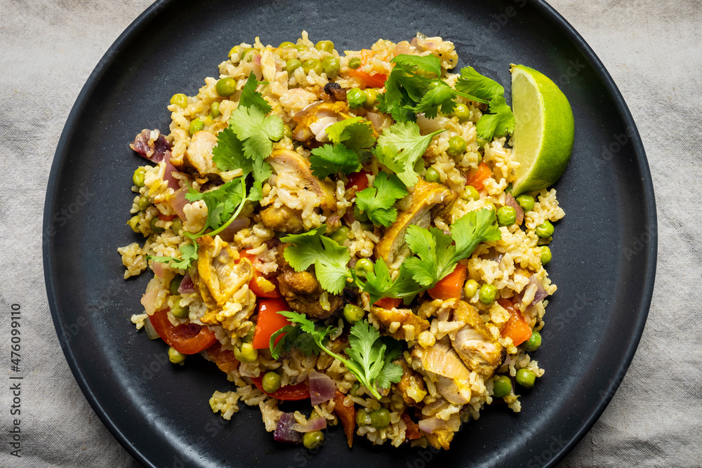 Chicken curry with green peas, red pepper, coriander, lime and basmati rice, served in a dark plate. Chicken curry with green peas, red pepper, coriander, lime and basmati rice, served in a dark plate.