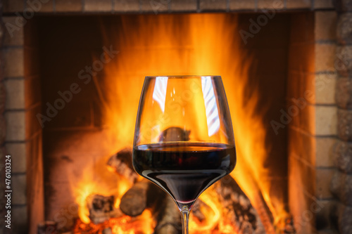 Christmas eve.Glass of Red wine near a cozy fireplace.