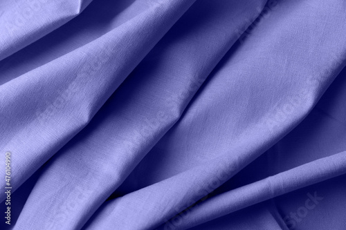 Textured folds of linen fabric in purple color. Textile background, top view, copy space