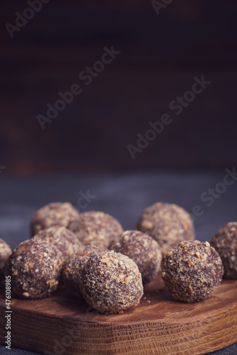 Healthy homemade energy balls on wooden plate. Vegan candies, sweets made of nuts and dates.