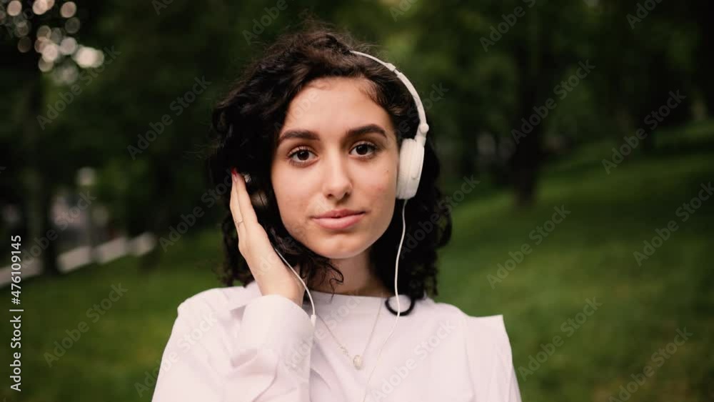 Close up of young millennial girl enjoying music in the park. Attractive young curly hair woman listening to music in headphone. High quality 4k footage Close up of young millennial girl enjoying music in the park. Attractive young curly hair woman listening to music in headphone. High quality 4k footage