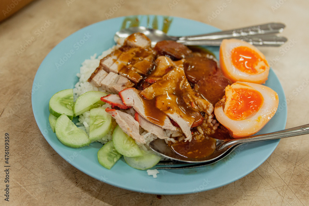 A plate with food contains eggs, chicken and vegetables. Bangkok, Thailand