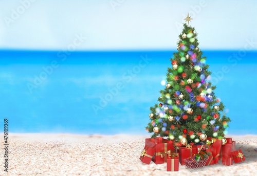 Christmas tree on the beach. Gift Boxes on sand beach shore. Decorated pine or fir tree.