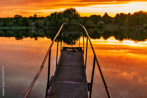 old iron footbridge on the lake at sunset