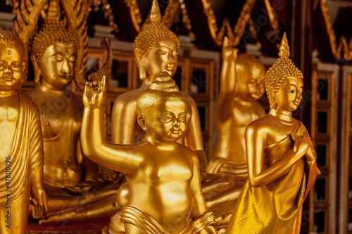 Golden statues of Buddha and a statue of a child pointing index finger up