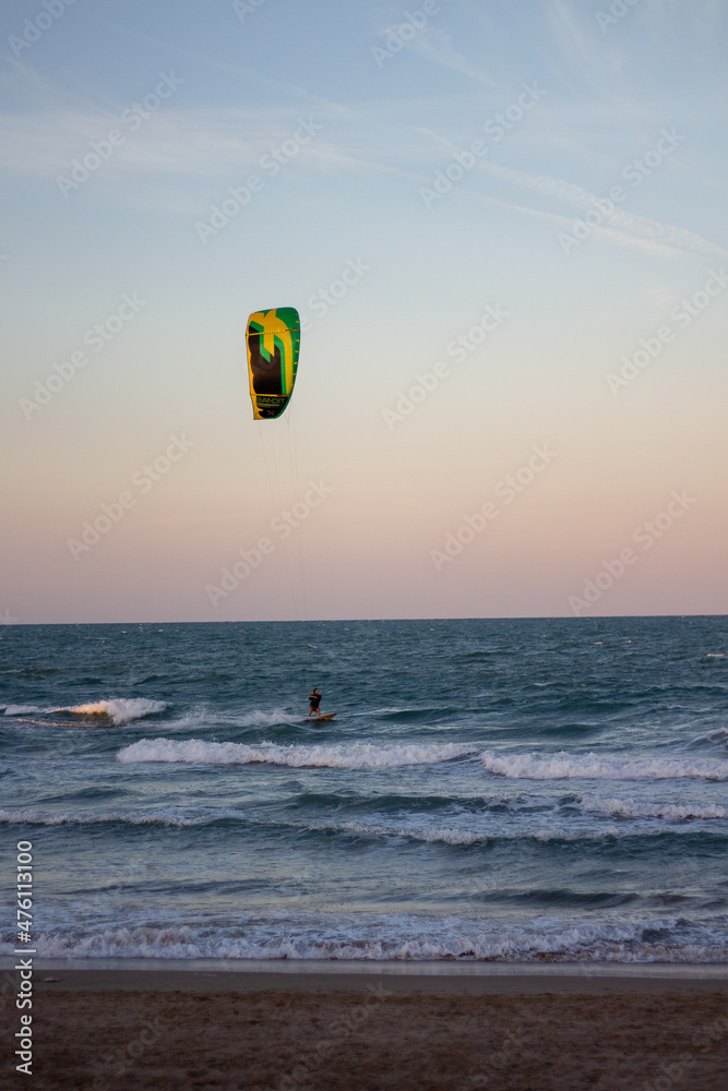 Windsurfing at sunset on a cullera beach. calm sea and vivid colors in the sky