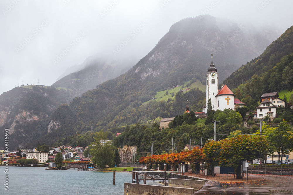 Quay, church and misty Swiss Alps. Mountains landscape in Flüelen, Switzerland.