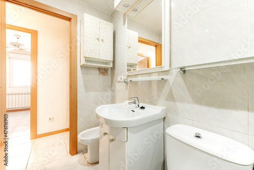 Bathroom with mirror and toilet with white furniture and lots of light in a holiday rental apartment