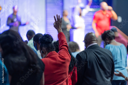 Valokuva African American Woman in a Red Outfit with Her Hand Raised in Church During Pra