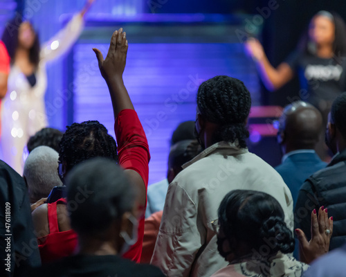African American Woman in a Red Outfit with Her Hand Raised in Church During Praise and Worship
