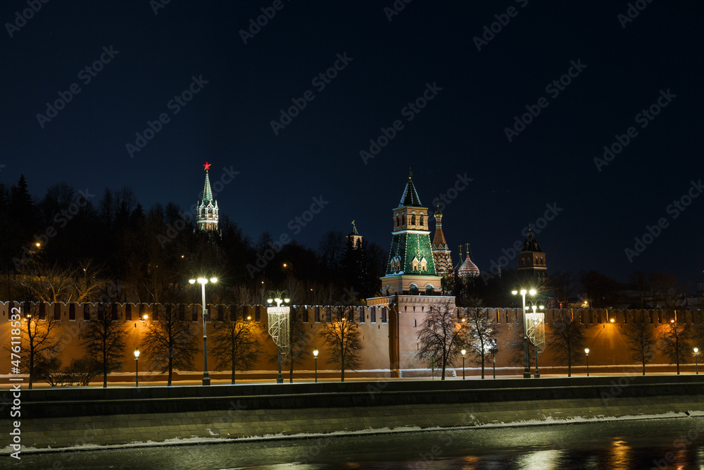 Obraz premium Moscow, Russia. Night view of The Kremlin: towers, wall, trees behind the wall. St. Basil's cathedral in background