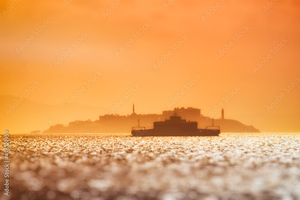 Silhouette of a ship in the setting sun on the background of the island. Sea ferry crossing in the Mediterranean Sea, maritime transport Europe. Postcard view, wallpaper.