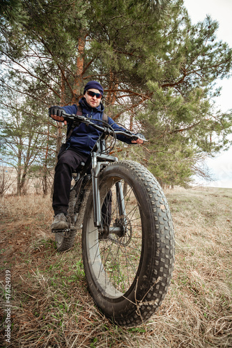 A man on a black fatbike with an electric motor. A favorite sports hobby of many people.
