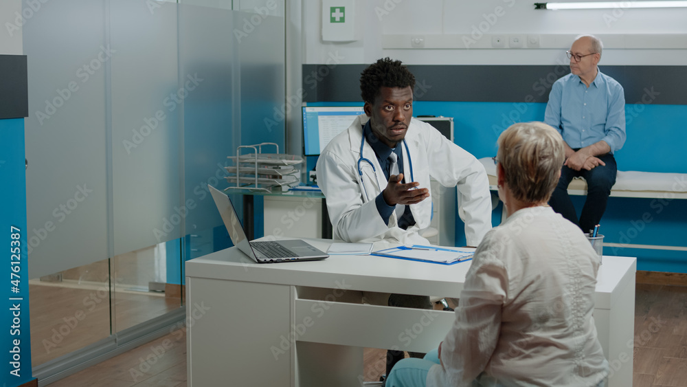 Nurse giving doctor x ray result for patient consultation in medical office at healthcare clinic. Young medic holding radiography, explaining diagnosis and disease to senior woman Nurse giving doctor x ray result for patient consultation in medical office at healthcare clinic. Young medic holding radiography, explaining diagnosis and disease to senior woman