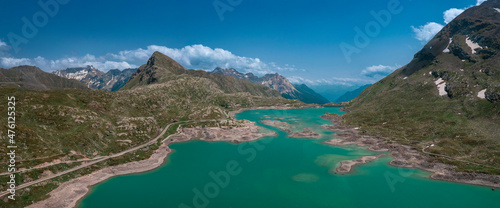 Mountain panorama at the reservoir lake Lago Bianco at the Bernina Pass with blue sky and sun from above in summer.