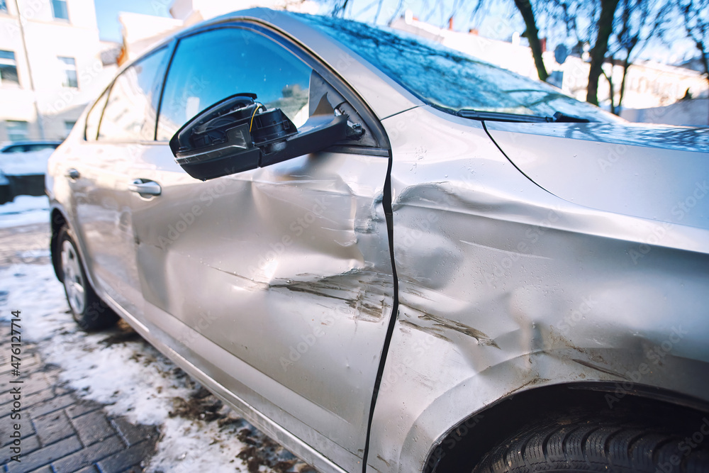 Car body side damage, traffic accident in winter season. Car door damage, broken and damaged side mirror on car door.