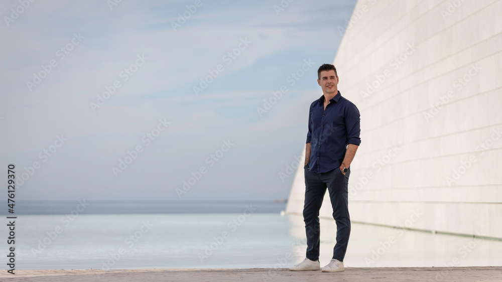 Portrait of a beautiful young man posing for a photo session along the tejo riverside in Lisbon, Portugal. Stylish freelance architect relaxing alone near the urban concept building in downtown. Portrait of a beautiful young man posing for a photo session along the tejo riverside in Lisbon, Portugal. Stylish freelance architect relaxing alone near the urban concept building in downtown.