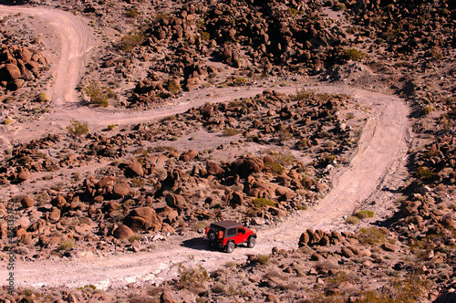 Jeep heading down winding desert trail.