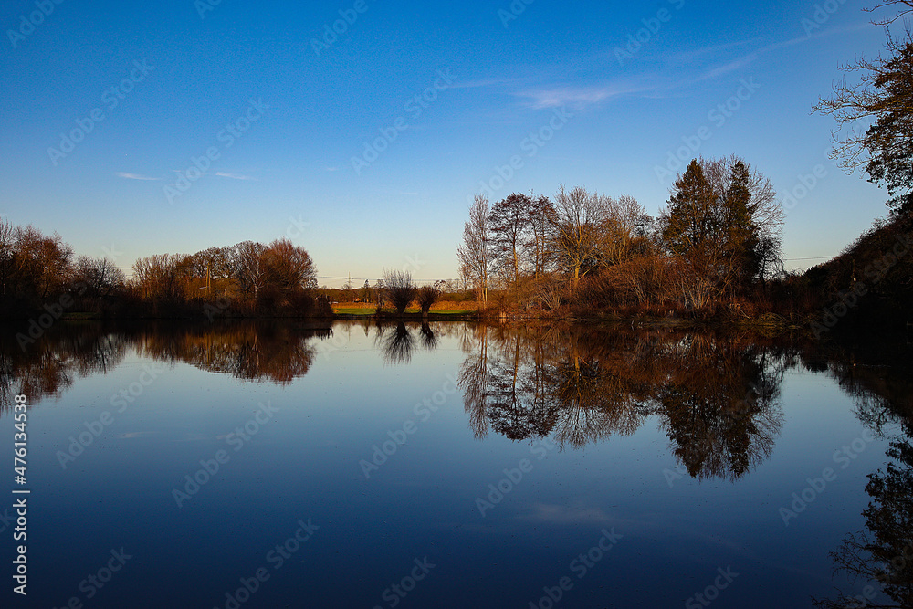 Still und starr ruht der See, - traumhafte Landschaft mit spiegelndem See unter blauem Himmel.