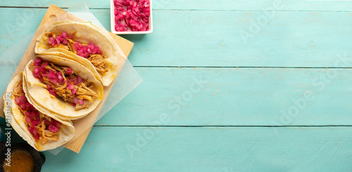Pork meat tacos called cochinita pibil on a turquoise background. Mexican food photo