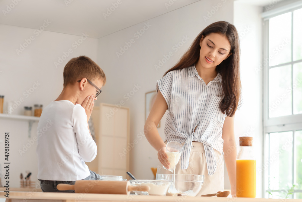 Teenage girl and her little brother preparing dough in kitchen Teenage girl and her little brother preparing dough in kitchen