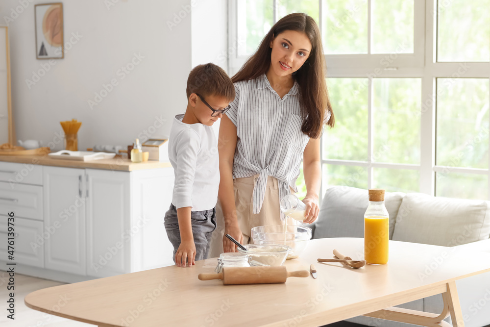 Teenage girl and her little brother preparing dough in kitchen Teenage girl and her little brother preparing dough in kitchen