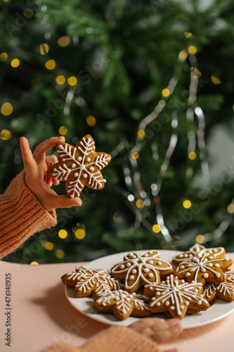 Ginger Christmas cookies in children's hands on the background of the Christmas tree.