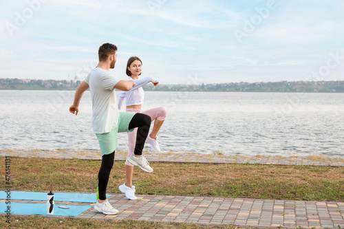Sporty young couple exercising near river