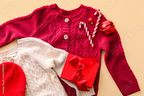 Stylish sweaters, hat, gift box and Christmas decor on color background, closeup © Pixel-Shot