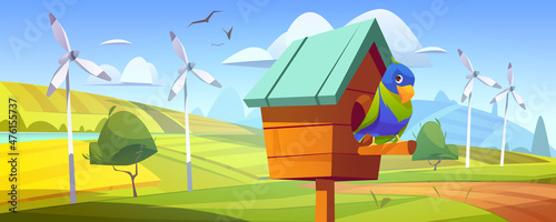 Canvastavla Cute parrot in birdhouse in countryside with green fields and wind turbines