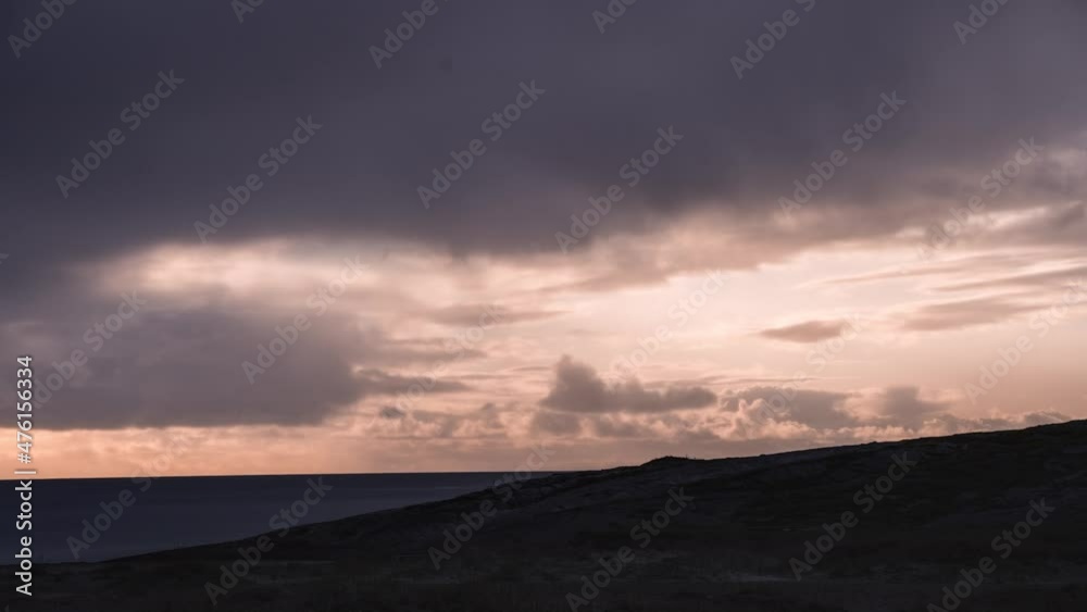 Pink and violet sunset above the sea. God-rays piercing through the thick clouds. A ferry passing on the horizon Pink and violet sunset above the sea. God-rays piercing through the thick clouds. A ferry passing on the horizon