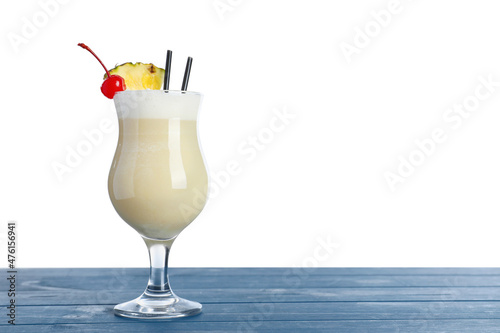 Tasty Pina Colada cocktail on blue wooden table against white background, space for text