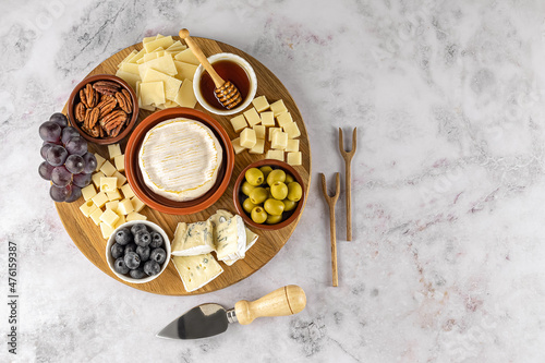 Top view of tasty charcuterie board with cheese, grape, nuts, olives, and ham on a circle kitchen plate photo
