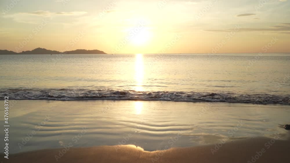 Beautiful scene of sunset at the beautiful beach of Thailand. White sand and the blue ocean waves coming back and forth with golden sunset in the background Beautiful scene of sunset at the beautiful beach of Thailand. White sand and the blue ocean waves coming back and forth with golden sunset in the background