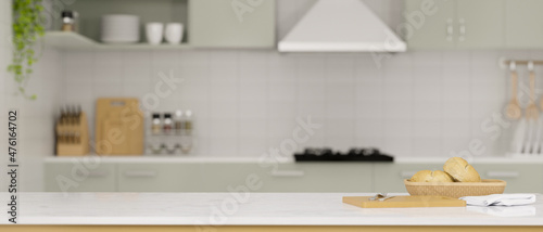 Modern white kitchen countertop with bread in a basket, chopping board and copy space