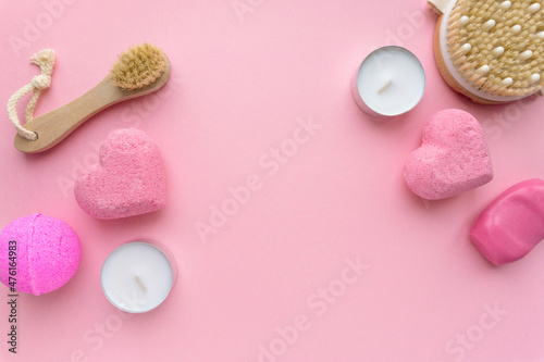 Set of spa products. Bath bombs, candles and massage brushes on pink background, space for text