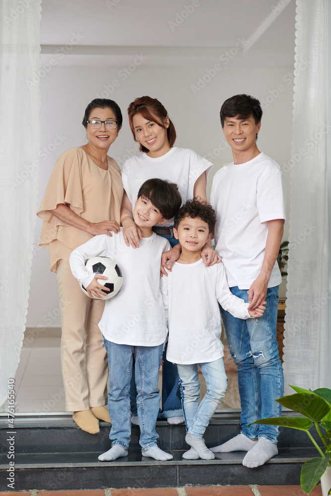 Grandmother, parents and two kids standing on house porch and smiling at camera Grandmother, parents and two kids standing on house porch and smiling at camera