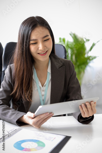 Asian woman sitting in the office and holding digital tablet
