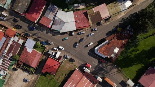 Aerial view from vertically above a busy intersection in Los Angeles de la Fortuna, Costa Rica. Drone footage of a small central American town with many vehicles driving and turning. photo