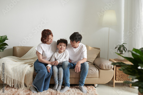 Happy parents and their smiling son in jeans sitting on sofa at home © DragonImages