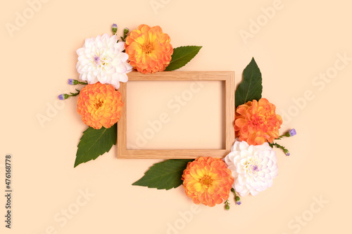 Flower border frame made of dahlia on a beige background. Springtime holidays composition with copyspace.